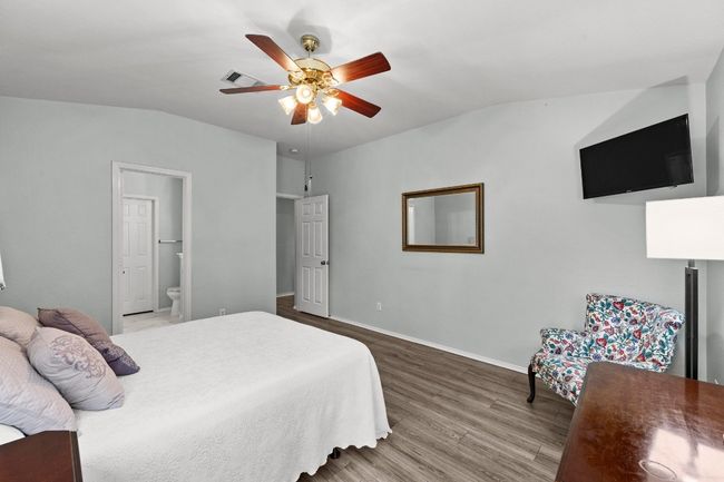 Bedroom with high ceiling, LVP floors, ensuite bathroom, and ceiling fan | Image 14