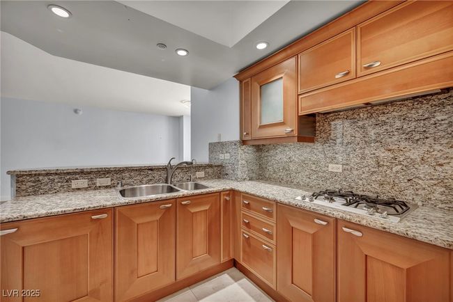 Kitchen with decorative backsplash, a sink, brown cabinets, and light stone counters | Image 27