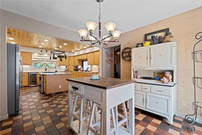 Kitchen with freestanding refrigerator, beverage cooler, dark flooring, a chandelier, and recessed lighting | Image 12