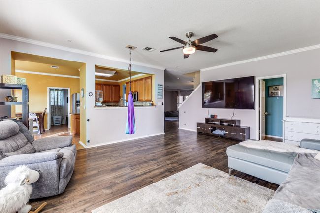 Living area with a ceiling fan, wood finished floors, crown molding, and baseboards | Image 6