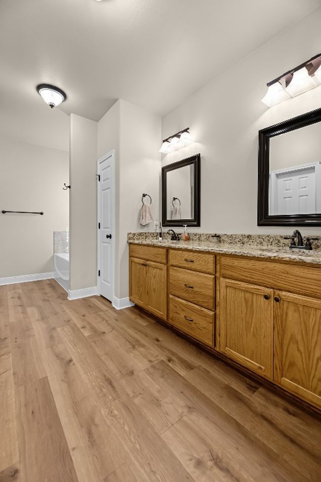Bathroom with a bath, baseboards, a sink, double vanity, and wood finished floors | Image 22