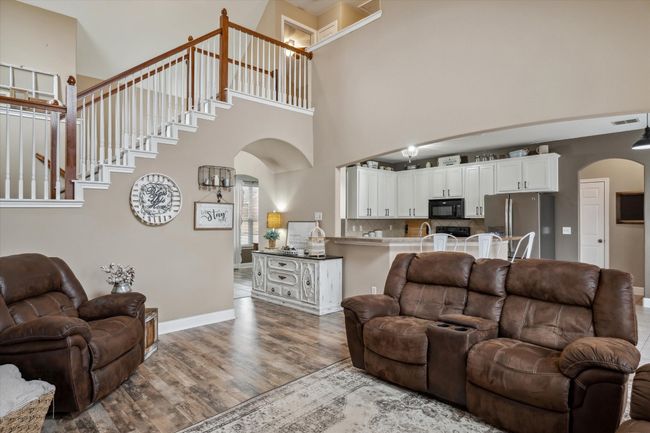 Living room with arched walkways, wood finished floors, a towering ceiling, visible vents, and baseboards | Image 7