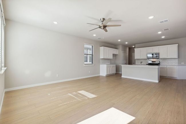 Unfurnished living room with a ceiling fan, light wood-style floors, recessed lighting, a sink, and baseboards | Image 8