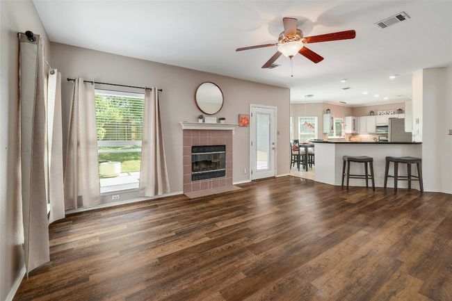 Unfurnished living room with ceiling fan, a fireplace, dark wood-type flooring, visible vents, and baseboards | Image 5
