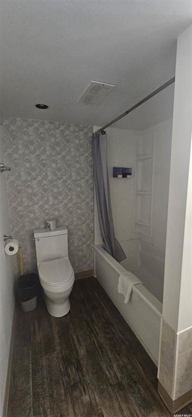 Bathroom featuring wood finished floors, shower / tub combo, and wallpapered walls | Image 22