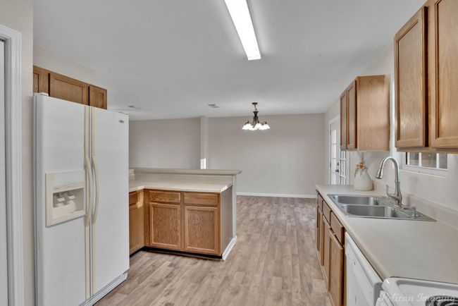 Kitchen with sink, hanging light fixtures, kitchen peninsula, a chandelier, and white appliances | Image 11