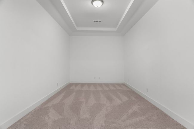 Empty room with light carpet, a raised ceiling, and baseboards | Image 18