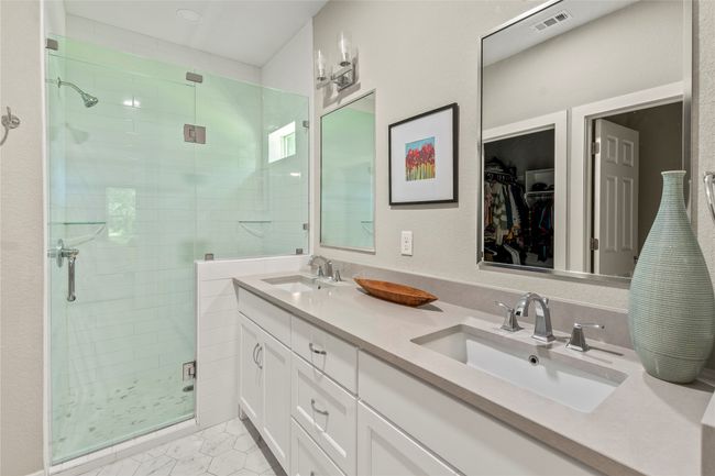 Features a glass-enclosed shower and dual sink vanity. | Image 10