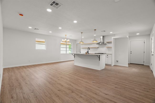 Kitchen featuring open shelves, a kitchen bar, recessed lighting, light wood-style floors, and white cabinets | Image 5