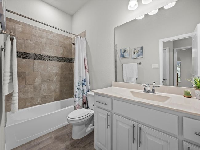 Bathroom featuring wood finished floors, vanity, and shower / bath combination with curtain | Image 25