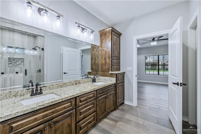 Bathroom with a ceiling fan, double vanity, a shower stall, and wood finished floors | Image 7