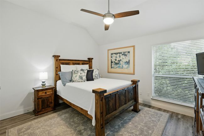Bedroom featuring wood-like finished floors, vaulted ceiling, and a ceiling fan | Image 25
