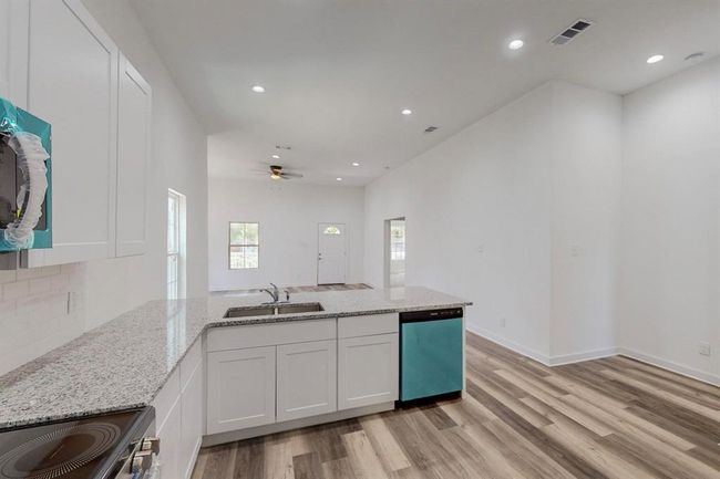 Kitchen featuring ceiling fan, light wood-type flooring, sink, white cabinets, and appliances with stainless steel finishes | Image 12