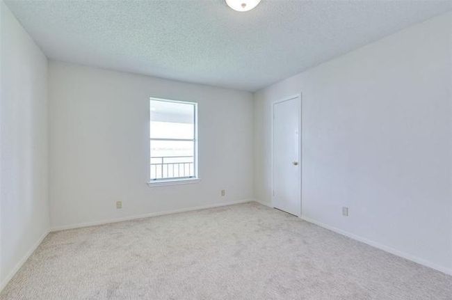 Bright, carpeted room with a simple design, featuring a single window and a door. Ideal for a bedroom or office space. | Image 15