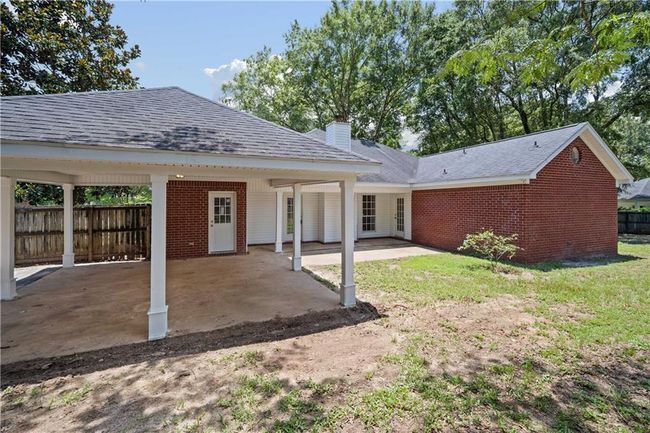 Back of property featuring brick siding, a chimney, a patio area, roof with shingles, and a carport | Image 27