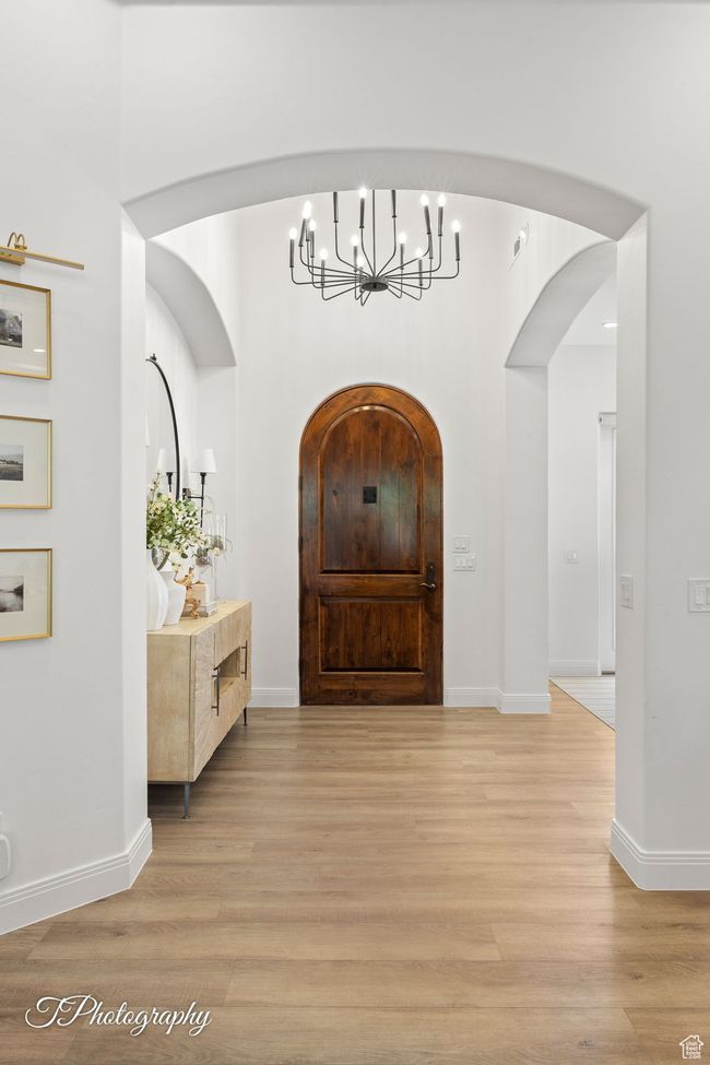 Foyer featuring a chandelier, light wood-style floors, arched walkways, and baseboards | Image 10