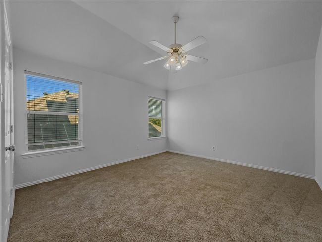 Carpeted empty room with a ceiling fan and lofted ceiling | Image 17