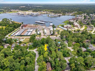 Aerial view of a mixed-use area with residential housing, industrial buildings, and a marina by a large body of water, with an arrow pointing downwards. | Image 1