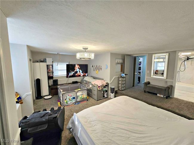 Carpeted bedroom with ensuite bath, a textured ceiling, and baseboards | Image 32