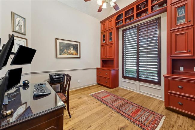 This private study is located just off the formal entry and features soaring built-in display cabinetry with convenient storage painted in this rich, bold hue. Plantation shutters finish the space and provide privacy without obstructing the ample natural light and scenic view. | Image 6