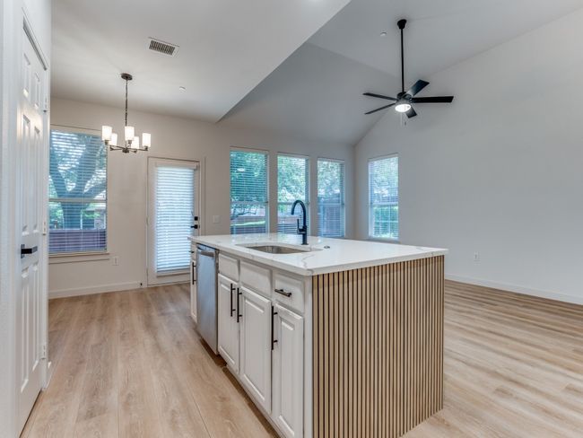 Kitchen with dishwasher, light wood-type flooring, a chandelier, pendant lighting, and a center island with sink | Image 14