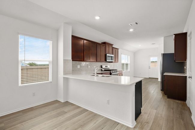 Kitchen featuring appliances with stainless steel finishes, tasteful backsplash, light wood-style floors, a sink, and recessed lighting | Image 7