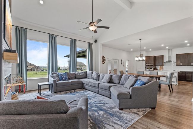 Living room featuring recessed lighting, light wood-style floors, ceiling fan with notable chandelier, beamed ceiling, and high vaulted ceiling | Image 13