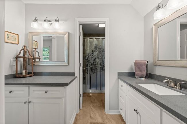 Bathroom features a modern design with dual vanities, sleek gray countertops, and white cabinetry. | Image 29