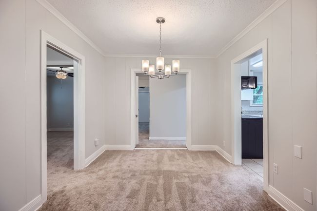 Unfurnished dining area with ornamental molding, a textured ceiling, a chandelier, and carpet floors | Image 9
