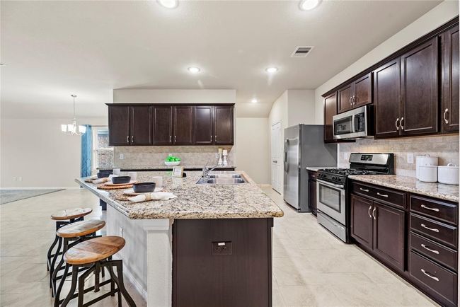 The sprawling island with breakfast bar seating serves as a versatile centerpiece, providing additional workspace, storage, and seating for casual dining or entertaining. | Image 5