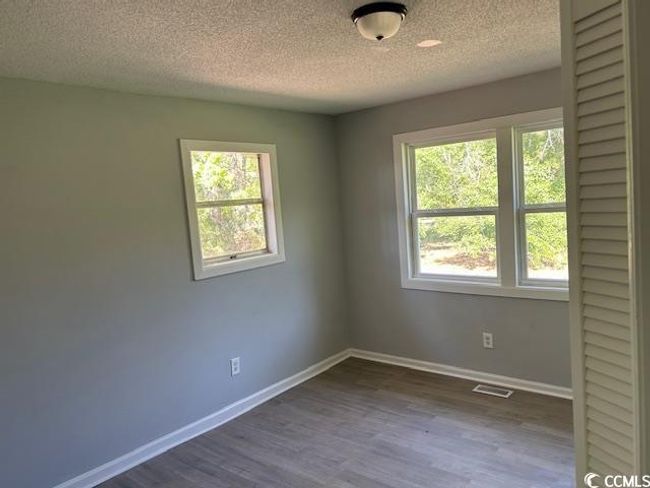 Spare room with plenty of natural light, a textured ceiling, dark wood-style flooring, and baseboards | Image 24