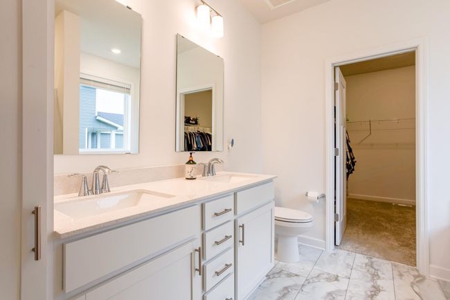 Elegant en suite bathroom with dual sinks, quartz countertops, and ample cabinetry for storage. | Image 19