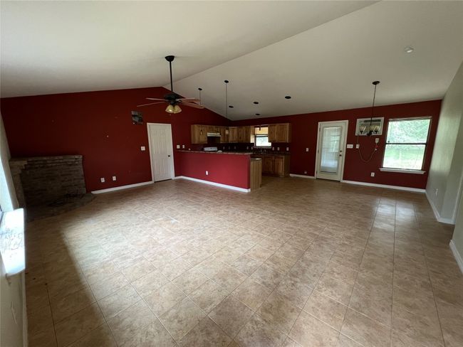 Unfurnished living room featuring a ceiling fan, vaulted ceiling, baseboards, and a chandelier | Image 7