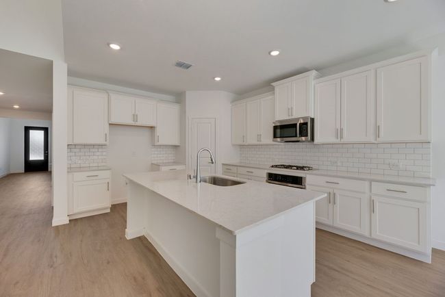Kitchen with appliances with stainless steel finishes, light wood-style floors, a kitchen island with sink, white cabinetry, and recessed lighting | Image 4