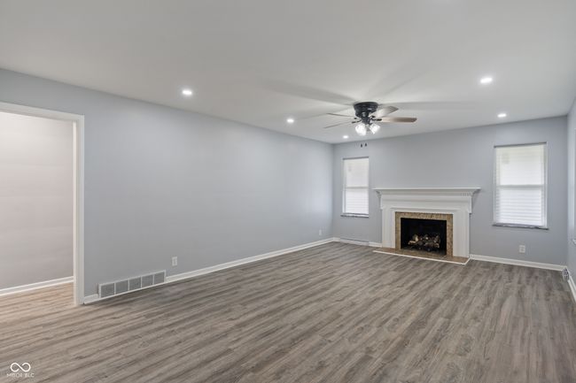 unfurnished living room with ceiling fan, wood finished floors, recessed lighting, baseboards, and a fireplace | Image 6