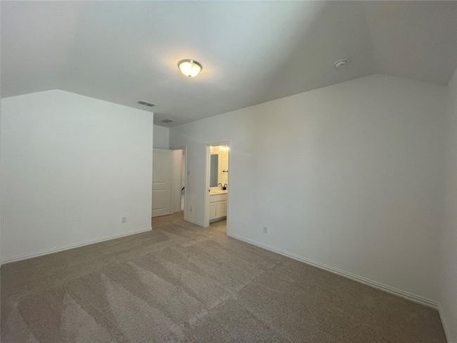 Unfurnished bedroom with lofted ceiling, light colored carpet, and ensuite bath | Image 24