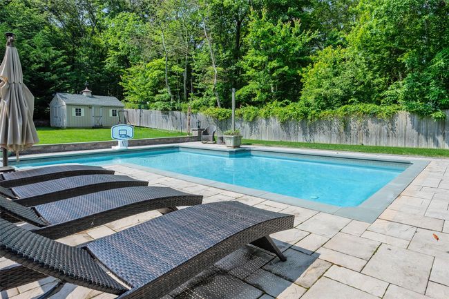 View of pool with a fenced backyard, a patio, and a storage shed | Image 42