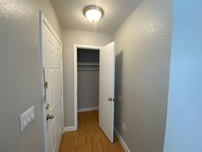 Hallway with light wood-type flooring, baseboards, and a textured wall | Image 4