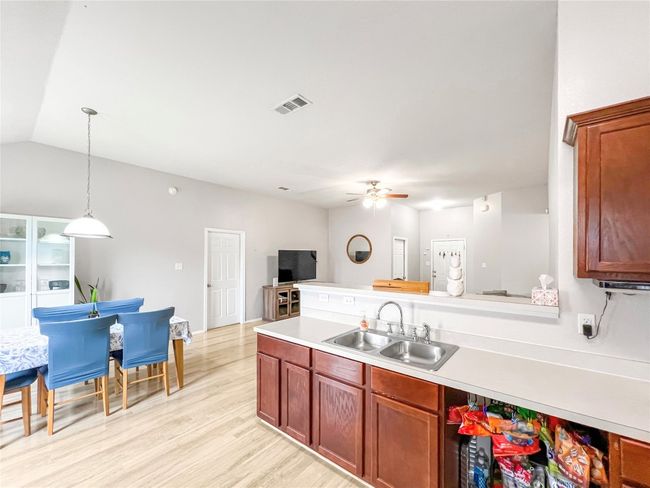Kitchen with a sink, ceiling fan, light countertops, light wood-style flooring, and pendant lighting | Image 15