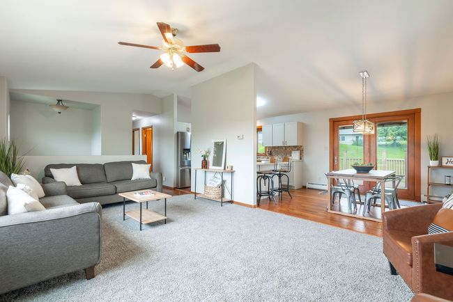 Carpeted living room featuring lofted ceiling, a ceiling fan, a baseboard radiator, a baseboard heating unit, and wood finished floors | Image 5