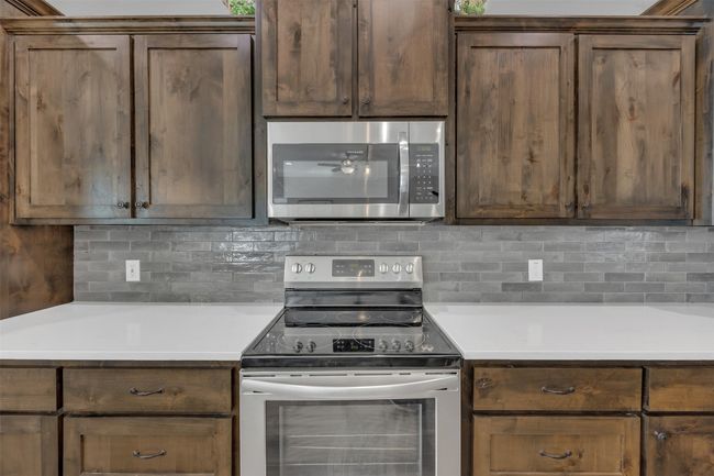 Kitchen featuring tasteful backsplash, appliances with stainless steel finishes, and light countertops | Image 15