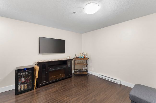 Living room featuring a baseboard radiator, baseboards, a textured ceiling, and dark wood-style floors | Image 11