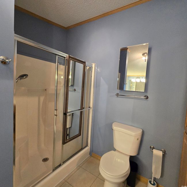 Full bath with tile patterned flooring, a stall shower, a textured ceiling, and ornamental molding | Image 26