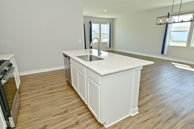 kitchen with light wood-style flooring, appliances with stainless steel finishes, a sink, and baseboards | Image 14
