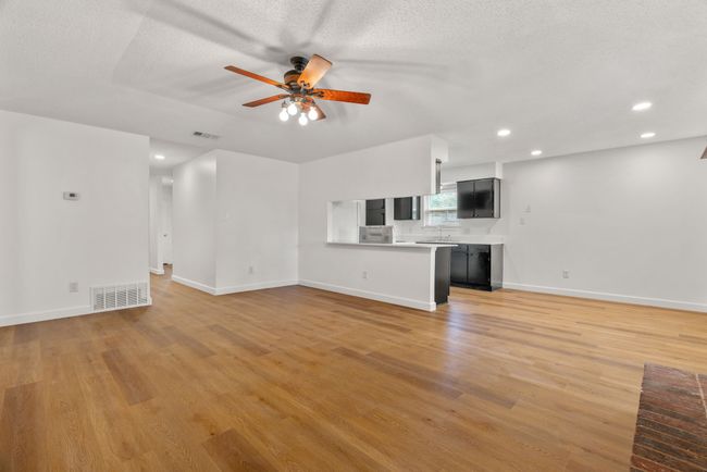 Unfurnished living room with ceiling fan, light wood-style flooring, recessed lighting, and a textured ceiling | Image 12