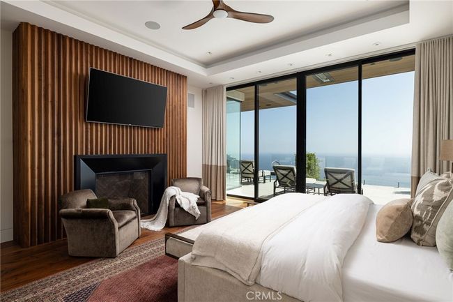 The primary bedroom is highlighted by a custom walnut-clad fireplace, custom closets, blackout shades, ceiling fan and priceless views. | Image 14