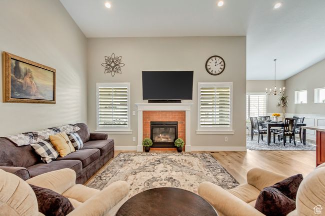 Living area with wood finished floors, a chandelier, a fireplace, lofted ceiling, and recessed lighting | Image 8