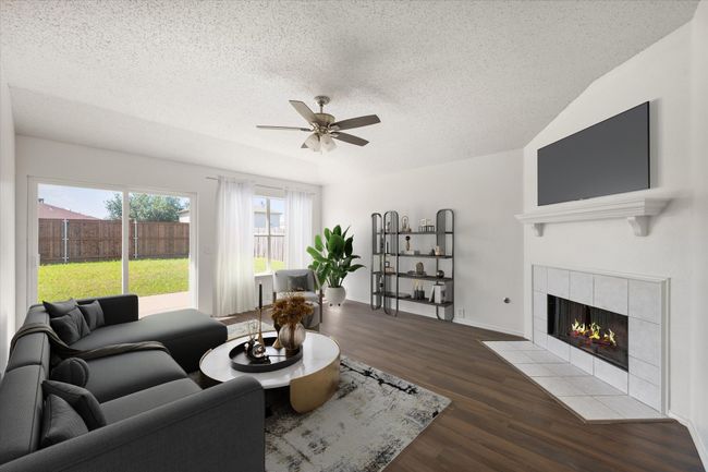 Computer staged den/iving area with a tile fireplace, ceiling fan, wood finished floors, and a textured ceiling | Image 10