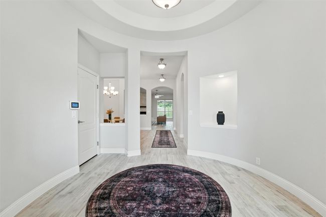 Foyer featuring light wood-type flooring, arched walkways, and a chandelier | Image 7
