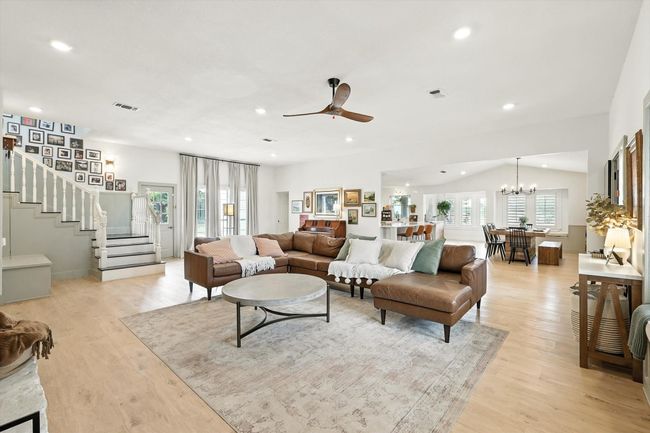 Living area with healthy amount of natural light, stairs, ceiling fan, vaulted ceiling, and a chandelier | Image 21